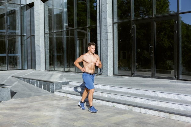 Young athletic runner man doing jogging outdoors. Cardio workout, healthy lifestyle