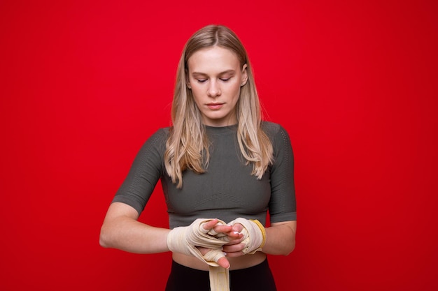 Young athletic woman bandages her hands before boxing training