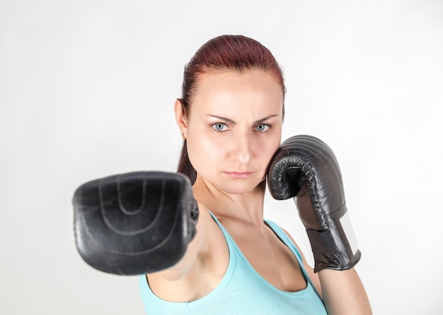 Young athletic woman fights with boxing gloves