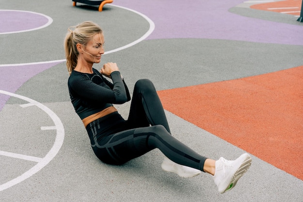 Photo young athletic woman is exercising on the sports ground