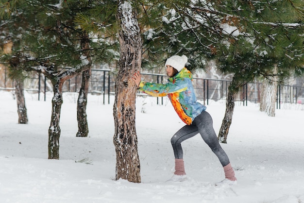 冷ややかな日に走る前に、若い運動女性がウォーミングアップしています。フィットネス、ランニング