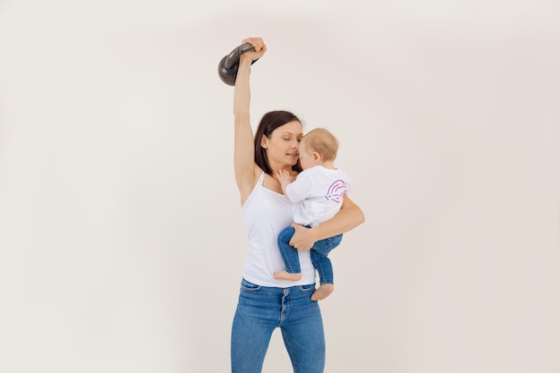 Foto giovane donna atletica che solleva il kettlebell e tiene un piccolo allenamento di forza del fondo bianco del bambino