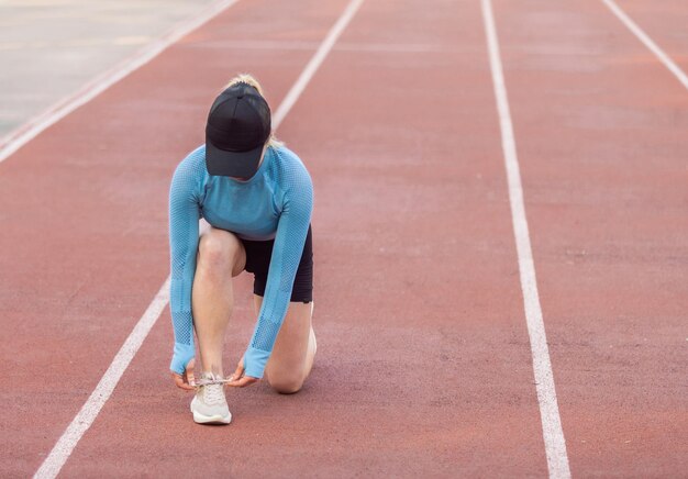 Photo young athletic woman tying the laces of sneakers at the stadium