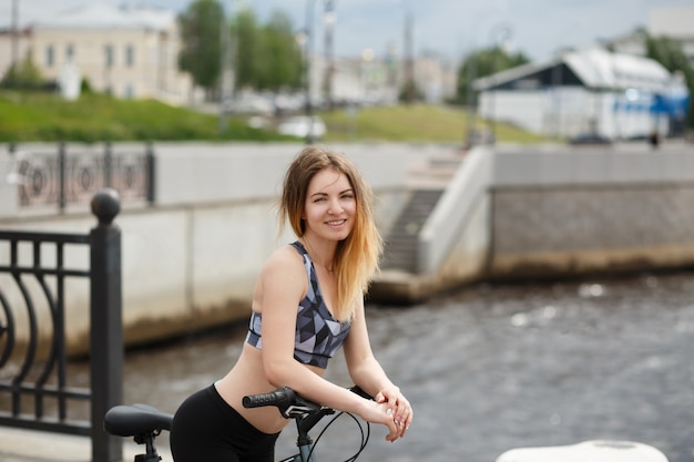 Young athletic woman wearing bicycle helmet, standing by bicycle