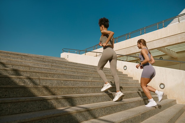 Photo young athletic women in sportswear are jogging around the city in morning reaching the goal