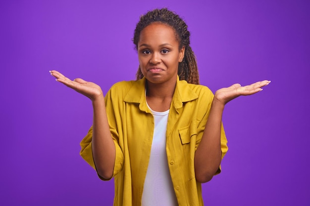 Young attractive african american woman throws up hands as sign uncomprehending