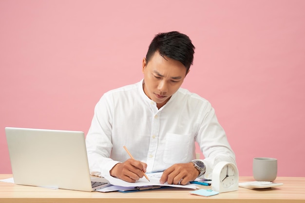 Young attractive asian businessman using laptop sitting on desk table in office