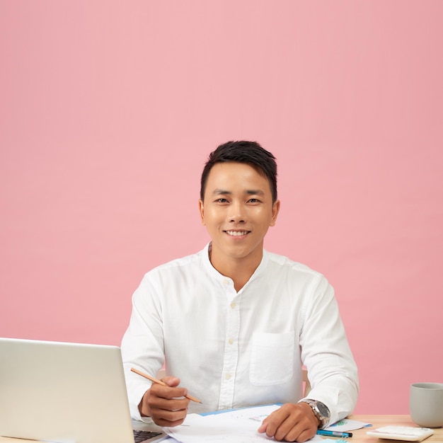 Young attractive asian businessman using laptop sitting on desk table in office