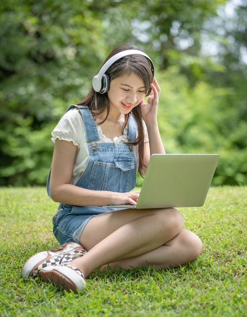 Young attractive asian female employee wear earphone listen to digital online course development study online in the park