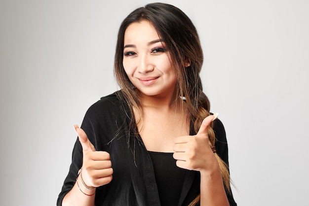 Young attractive asian kazakh brunette woman smiling and showing thumbs up isolated on white background