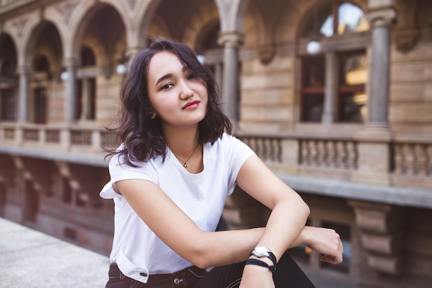 Молодая привлекательная азиатская женщина в белой футболке и черных джинсах в историческом здании
