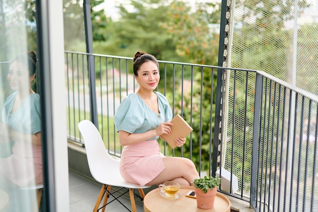 Young attractive Asian woman reading a book on balcony 