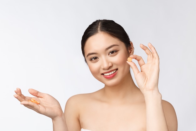 Young attractive asian woman who takes a capsule or pill Isolated over  