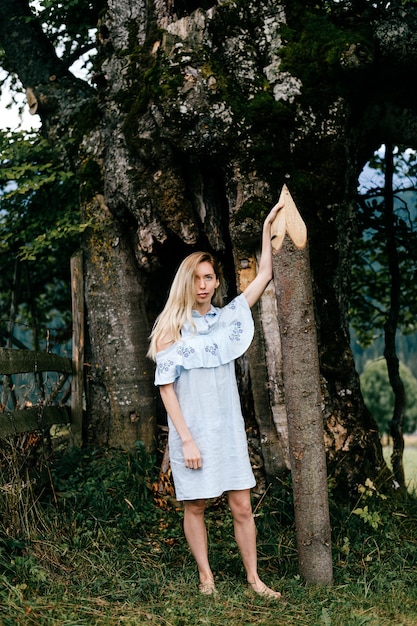 사진 오래 된 나무 근처 지분과 함께 포즈 블루 로맨틱 드레스에 젊은 매력적인 맨발의 금발 소녀