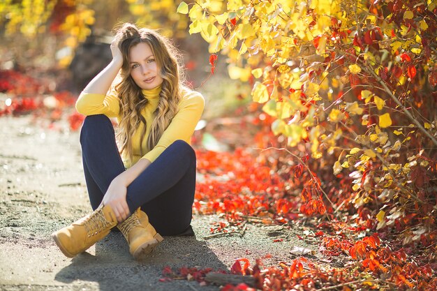 Young attractive blond woman outdoors on fall background. Autumn portrait of beautiful stylish woman.