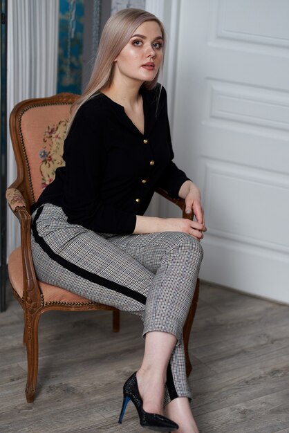 Young attractive blond woman wearing business clothes sitting on a chair