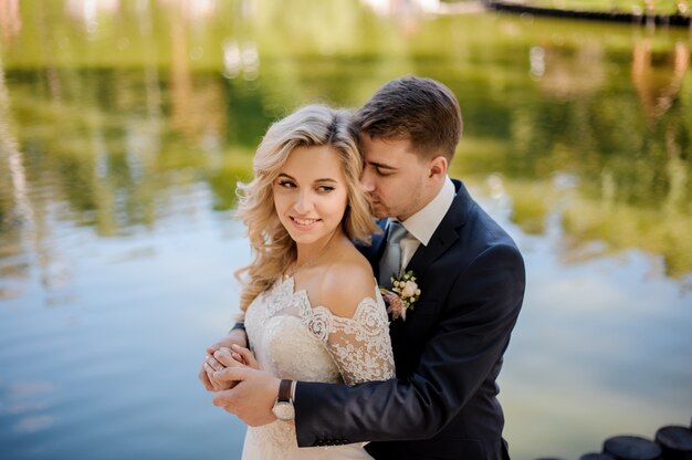 Young and attractive bride with bridegroom on the river bank