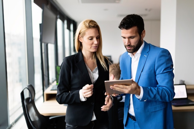 Young attractive business couple using tablet in their company