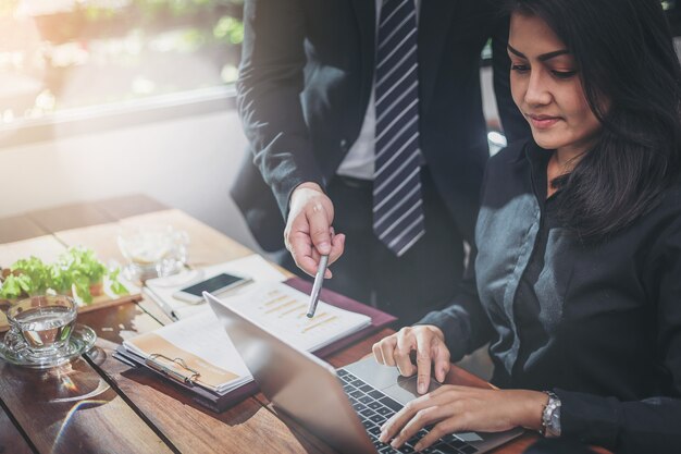 Young attractive business woman working with laptop has been guided by her colleague.