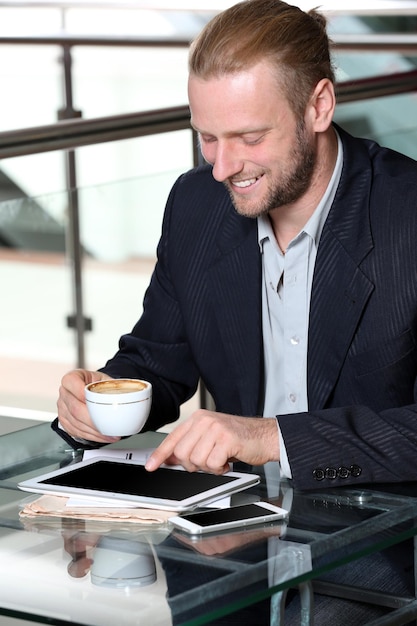 Photo young attractive businessman having lunch and working in a cafe