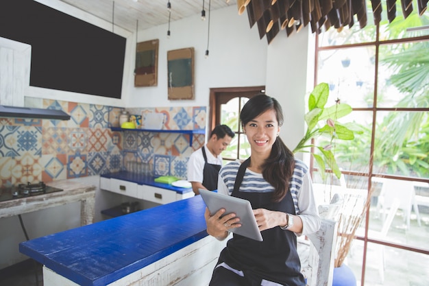 タブレットで若い魅力的なカフェのオーナー