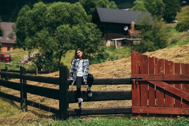 A young attractive caucasian female sitting on a fence