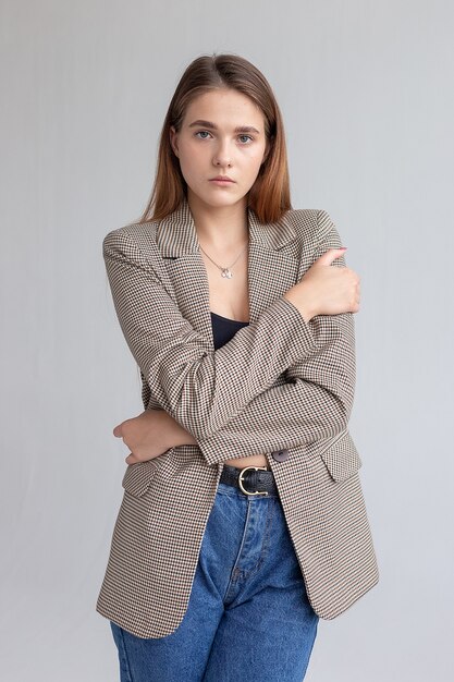 Young attractive caucasian woman with long brown hair in suit jacket at studio