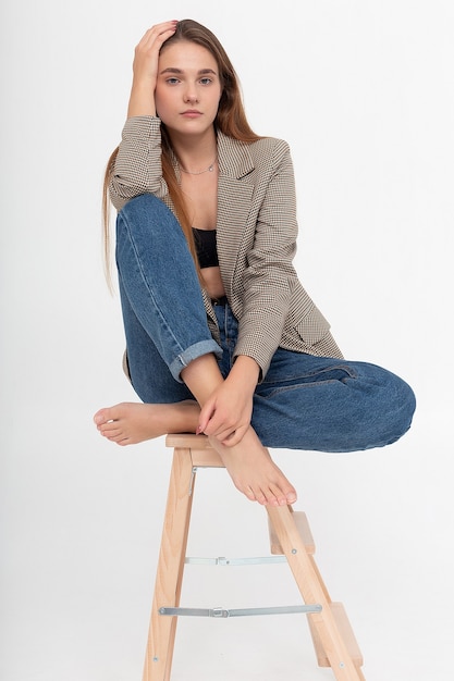 Young attractive caucasian woman with long brown hair in suit jacket at studio