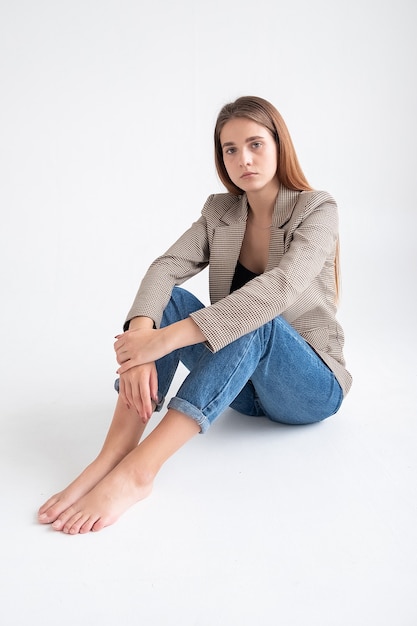 Young attractive caucasian woman with long brown hair in suit jacket at studio