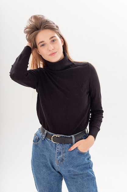 Young attractive caucasian woman with long hair in black turtleneck, blue jeans