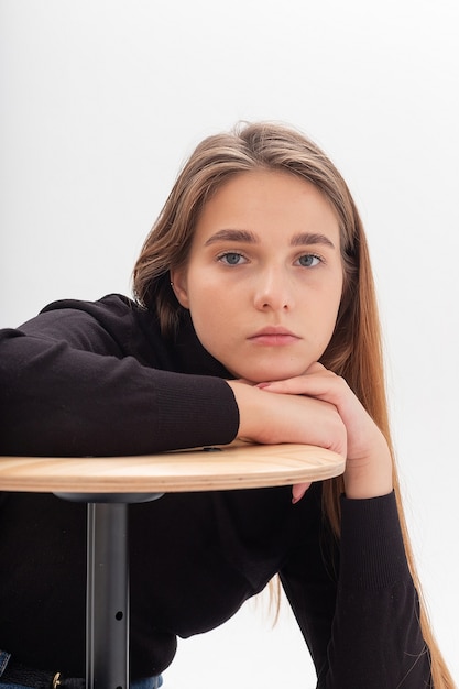 young attractive caucasian woman with long hair in black turtleneck on white studio background