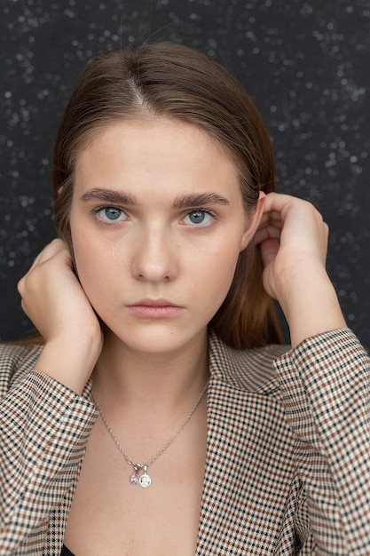 Foto giovane donna caucasica attraente con capelli lunghi, occhi azzurri in giacca davanti alla bandiera dello studio