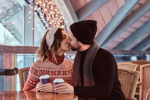 Photo young attractive couple on a date in an ice skating rink, kiss while sitting at the table in the hall