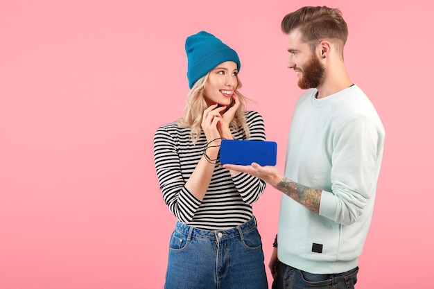 Young attractive couple listening to music on wireless speaker