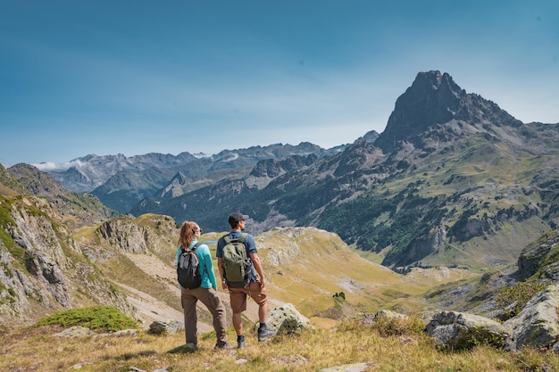 Young attractive couple looking the panoramic views of the amazing mountains landscape in summer dis