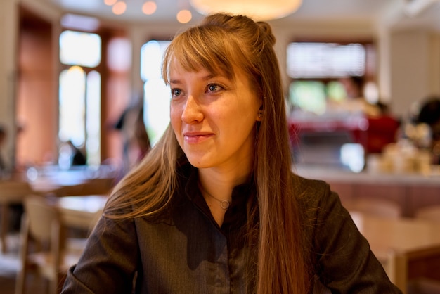 Young attractive european female looking away in coffee shop pensive calm thoughtful