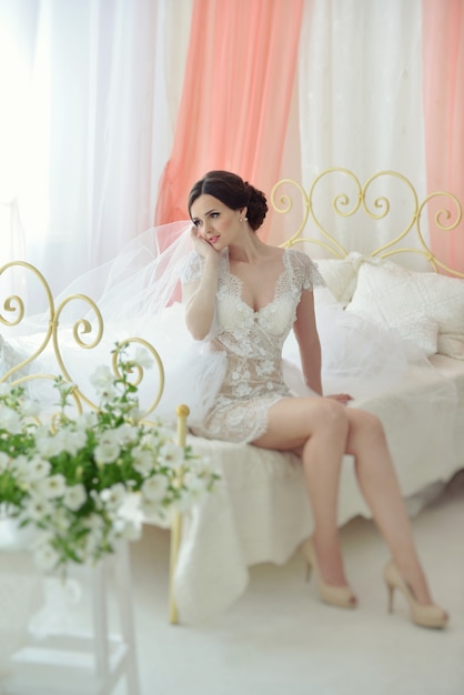 Young attractive female model girl before the wedding sitting on the bed.