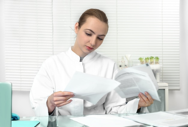 Young attractive female scientist or graduate student reads scientific paper