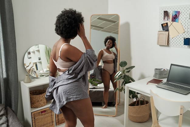 Young attractive female in underwear looking in mirror