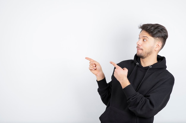 Young attractive funny man in casual clothes pointing away