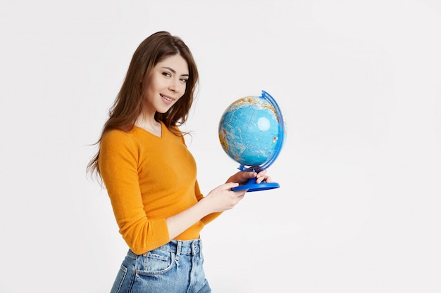 A young attractive girl chooses a place to rest on a large globe