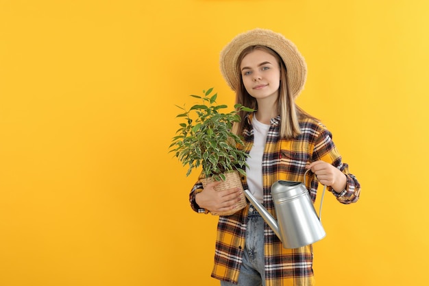 Young attractive girl gardener on yellow background