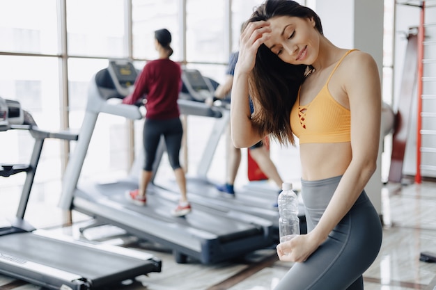 Young attractive girl in the gym drinking water