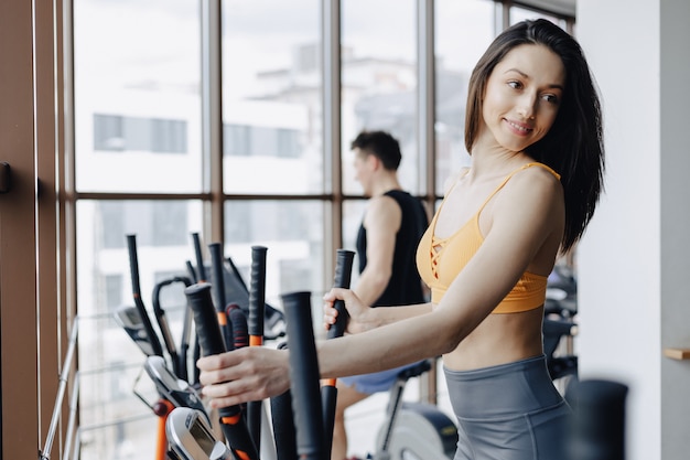 Young attractive girl at gym on exercise bike, fitness and yoga