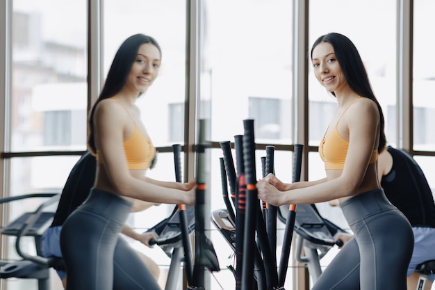 Young attractive girl at gym on exercise bike, fitness and yoga