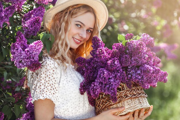 屋外で魅力的な若い女の子。ライラックの花束を持つ女性。明るい女性のクローズアップの肖像画