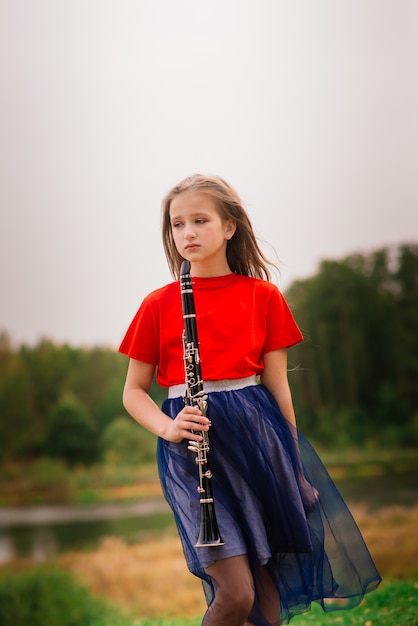 Photo young attractive girl playing clarinet, ebony in fall park