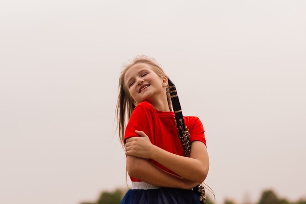 Giovane ragazza attraente che suona il clarinetto, ebano nel parco autunnale