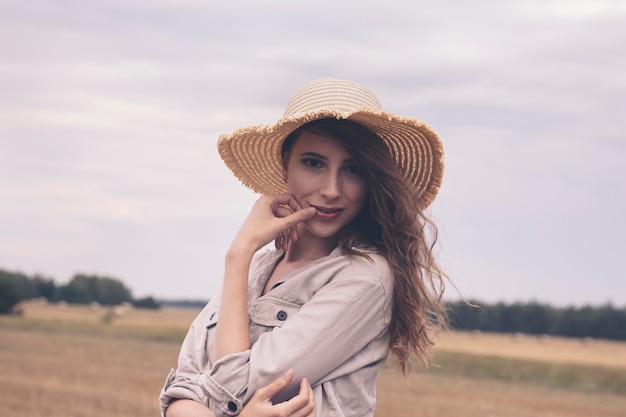 Young attractive girl in a straw hat in a field