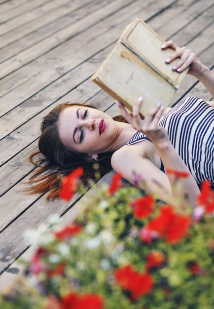 Foto giovane ragazza attraente che studia e legge un libro su un pavimento di legno